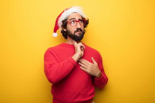 Jonge gekke bebaarde man met rode bril en hoed van de Kerstman