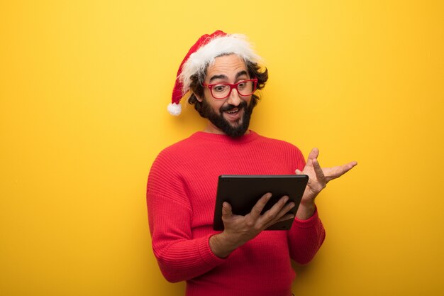 Jonge gekke bebaarde man met rode bril en hoed van de Kerstman