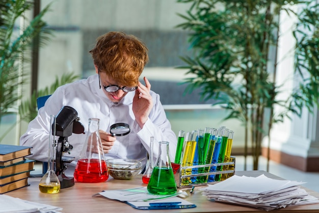 Jonge gekke chemicus die in het laboratorium werkt