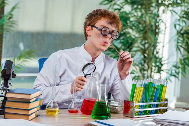 Jonge gekke chemicus die in het laboratorium werkt