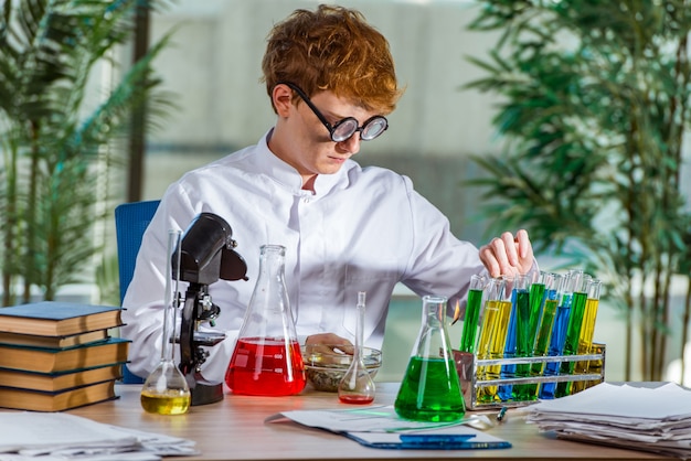 Jonge gekke chemicus die in het laboratorium werkt