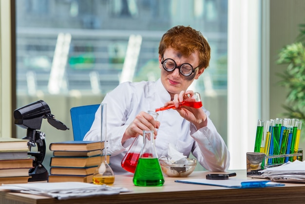 Jonge gekke chemicus die in het laboratorium werkt