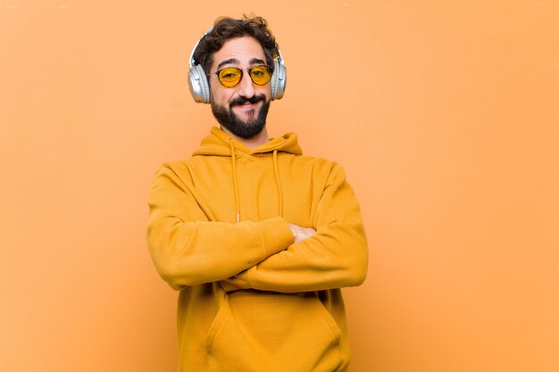 Jonge gekke cool man luisteren muziek met koptelefoon op oranje muur