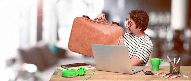 Jonge gekke grafische ontwerper op een bureau met laptop