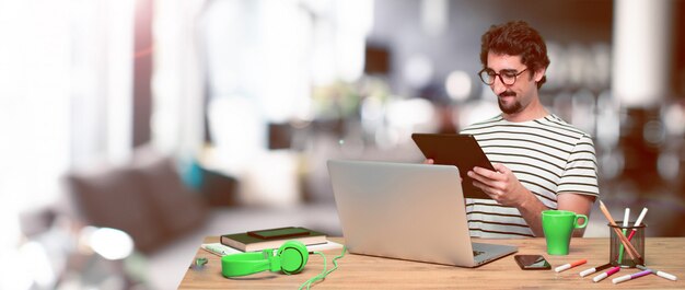 Jonge gekke grafische ontwerper op een bureau met laptop