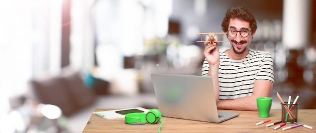 Jonge gekke grafische ontwerper op een bureau met laptop