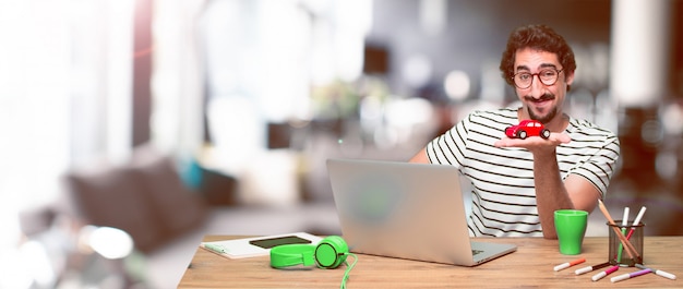 Jonge gekke grafische ontwerper op een bureau met laptop