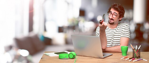 Jonge gekke grafische ontwerper op een bureau met laptop