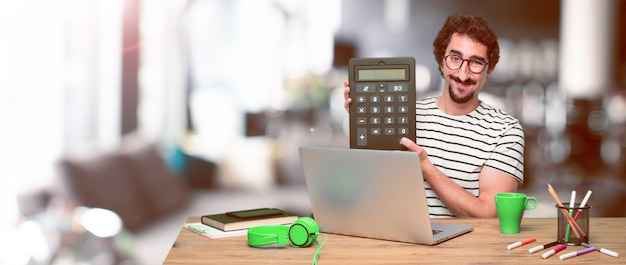 Jonge gekke grafische ontwerper op een bureau met laptop