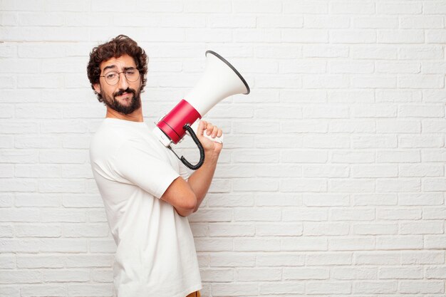 Jonge gekke man met een megafoon tegen de muur.