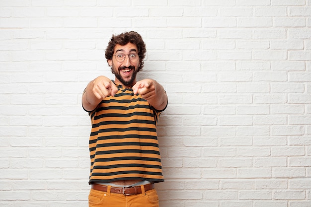 Jonge gekke of dwaze mens die en emoties tegen bakstenen muurachtergrond gesturing uitdrukken