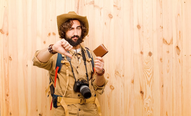 Jonge gekke ontdekkingsreiziger met strohoed en rugzak op houten achtergrond
