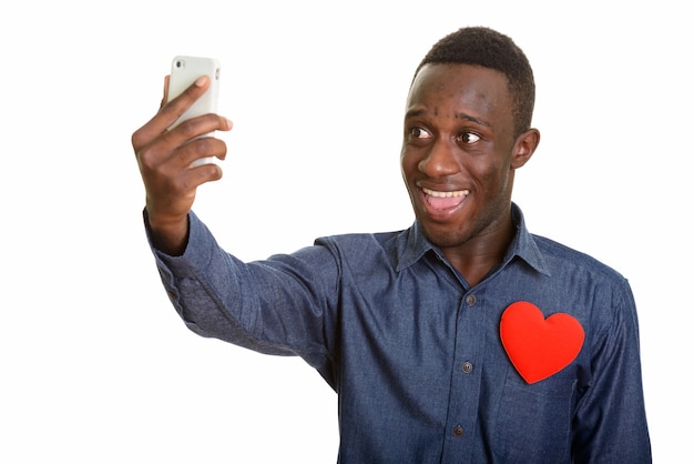 Jonge gelukkig Afrikaanse man die lacht tijdens het nemen van selfie met mobiel