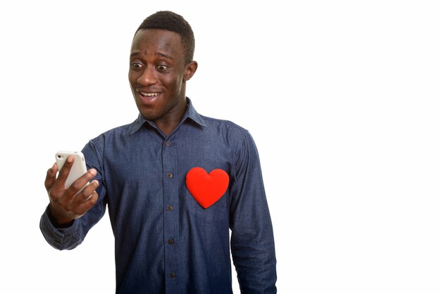 Jonge gelukkig Afrikaanse man glimlachend en met behulp van mobiele telefoon