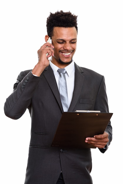 Jonge gelukkig Afrikaanse zakenman glimlachen tijdens het lezen op klembord en praten over de mobiele telefoon