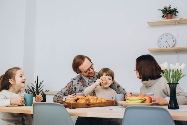 Jonge gelukkig gezin met twee kinderen samen ontbijten.