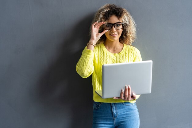 Jonge gelukkig lachende vrouw in casual kleding met laptop en het verzenden van e-mail naar haar beste vriend.