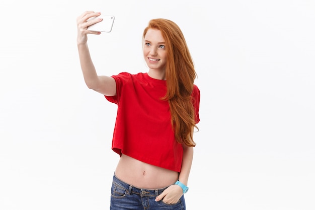 jonge gelukkig roodharige vrouw geïsoleerd op witte muur achtergrond maken selfie