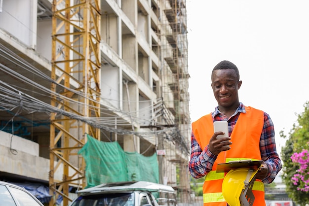 Jonge gelukkig zwarte Afrikaanse man bouwvakker lachend en ons