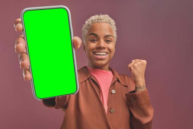 Jonge gelukkige afro-amerikaanse vrouw verheugt zich over het ontvangen bericht in de telefoon