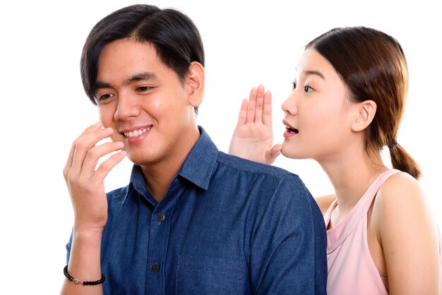 jonge gelukkige Aziatische paar lachend met vrouw fluisteren naar de mens