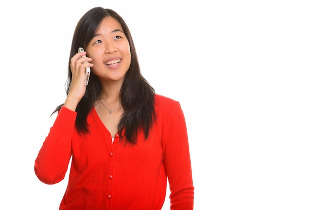 Jonge gelukkige Aziatische vrouw die op geïsoleerde mobiele telefoon spreekt