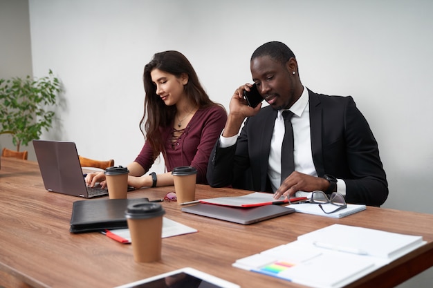 Jonge gelukkige bedrijfsmensen die in modern bureau, multi-etnisch groepswerk samenwerken. man bellen met smartphone