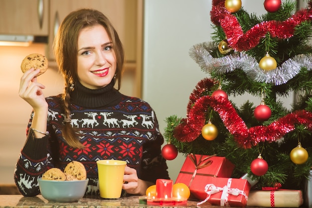 Jonge gelukkige de chocoladekoekjes van de vrouwenholding dicht bij de Kerstboom