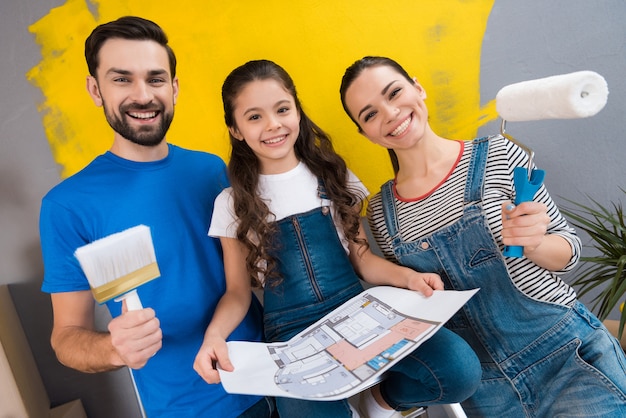 Jonge gelukkige familie die reparaties in het huis voor verkoop doet