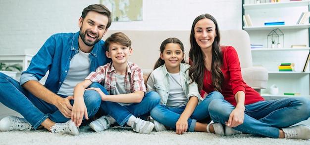 Jonge gelukkige familie ontspannen samen thuis glimlachend en knuffelen zittend op de vloer