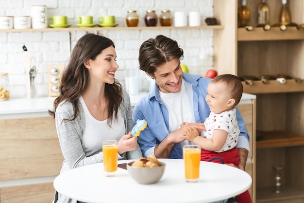 Jonge gelukkige familie samen ontbijten, 's ochtends in de keuken zitten