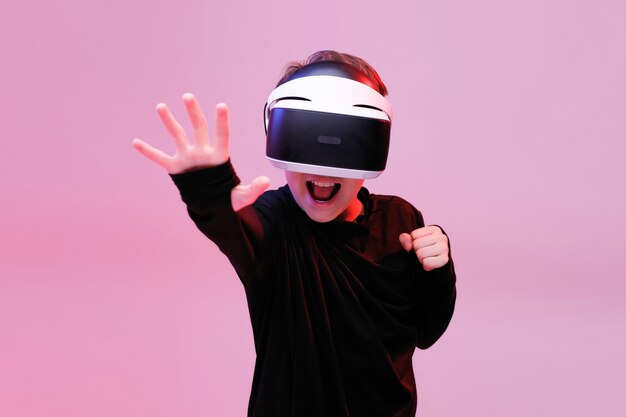 Jonge gelukkige jongen in een bril van virtual reality op neol lichte achtergrond