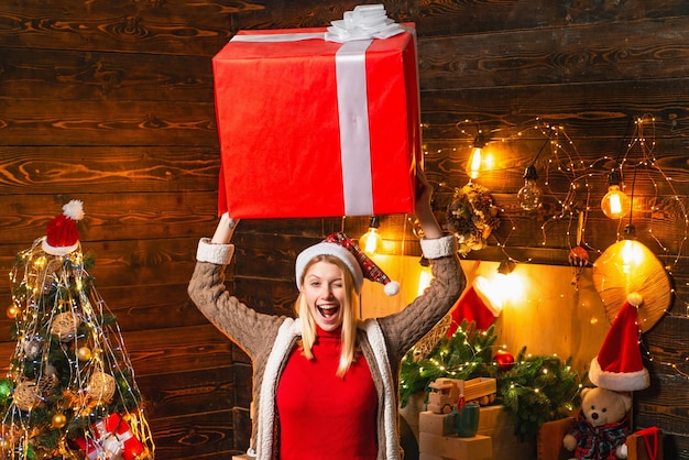 Jonge gelukkige kerstman houdt een geweldige kerstcadeaudoos vast Prettig kerstinterieur voor de feestdagen