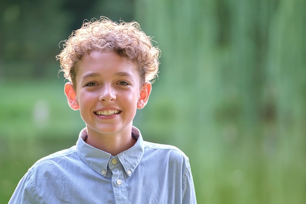 Jonge, gelukkige kindjongen die ontspant in het zomerpark Positief kind dat van de zomer in de buitenlucht geniet. Kinderwelzijnsconcept