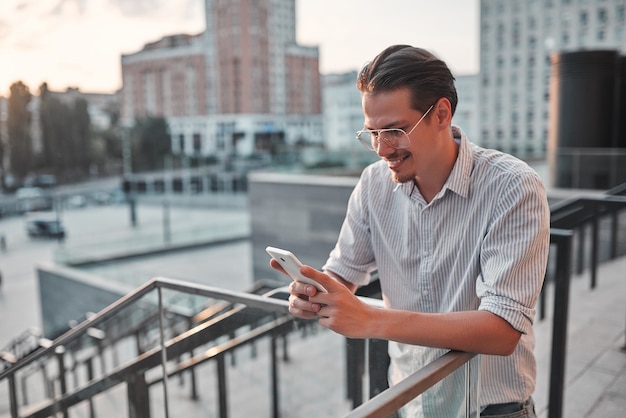 Jonge gelukkige man met een telefoon in zijn hand en glimlachend.