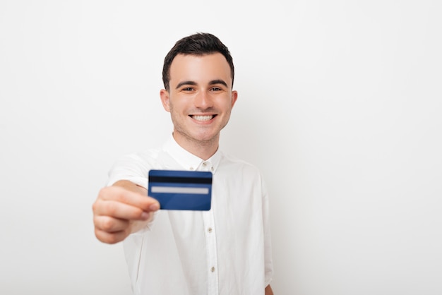 Jonge gelukkige mens die een creditcard op witte achtergrond houdt