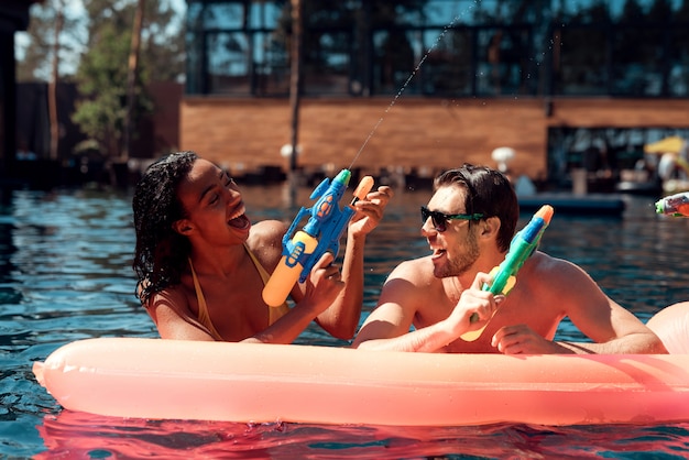 Jonge gelukkige mensen die samen met kleurrijk water spelen