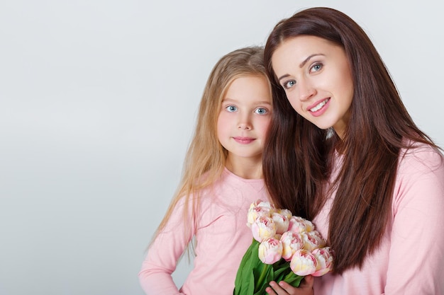 Jonge gelukkige moeder en dochter met boeket tulpen