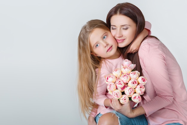 Jonge gelukkige moeder en dochter met boeket tulpen