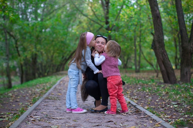 Jonge gelukkige moeder met haar dochters in het park veel plezier