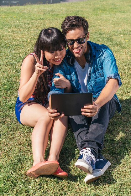 Jonge gelukkige paar met behulp van tablet zitten in het park