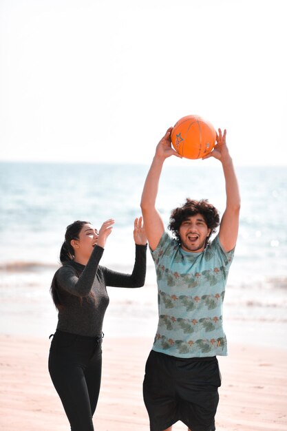 jonge gelukkige paar voetballen op strand Indiase Pakistaanse model