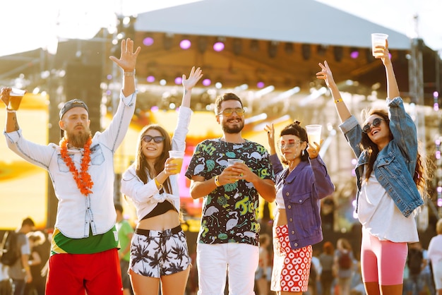 Jonge gelukkige vrienden die bier drinken en samen plezier hebben op het muziekfestival Vriendschap