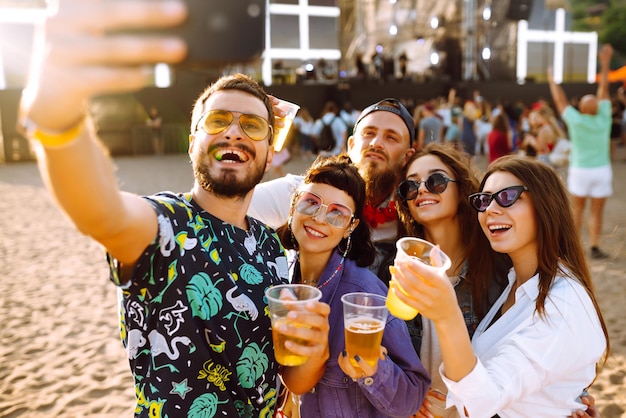 Jonge gelukkige vrienden die bier drinken en samen plezier hebben op het muziekfestival Vriendschap