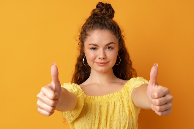 Foto jonge gelukkige vrolijke vrouw duim opdagen in studio