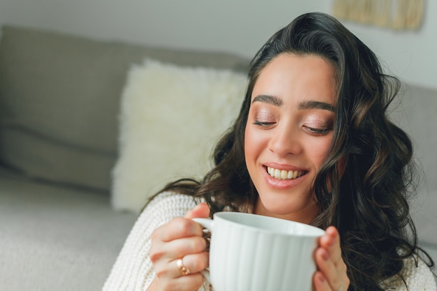 Jonge gelukkige vrouw die een kopje thee drinkt