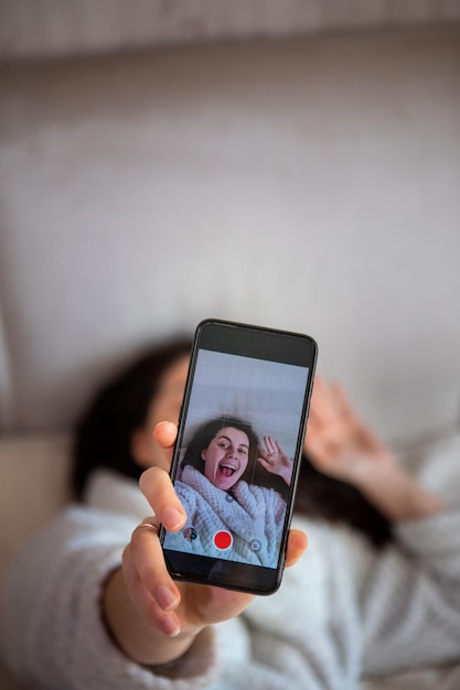 Jonge gelukkige vrouw die een selfie-verhaal in bed neemt