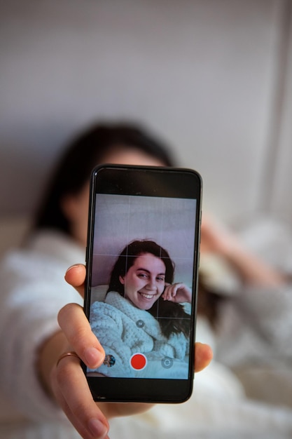 Jonge gelukkige vrouw die een selfie-verhaal in bed neemt