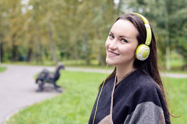 Jonge gelukkige vrouw het luisteren muziek van smartphone met hoofdtelefoons in een stil Park