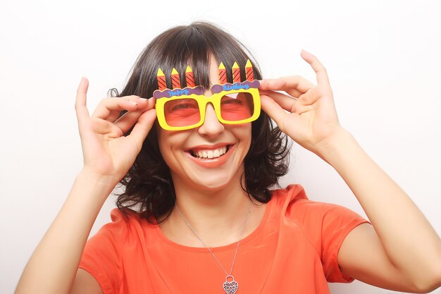 Jonge gelukkige vrouw met grote oranje zonnebril, klaar voor feest